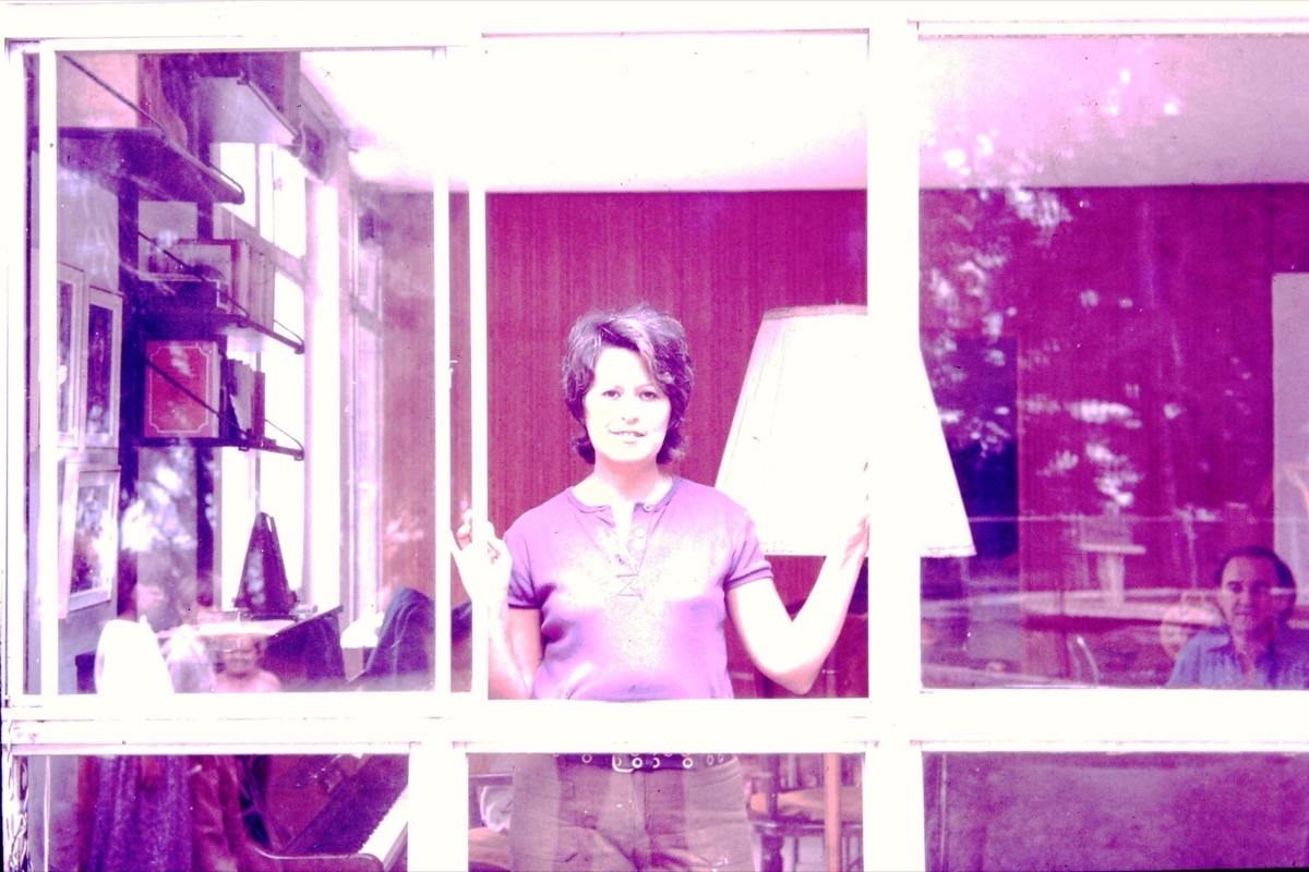 Выцветший цветной снимок 1970-х: женщина за стеклянной дверью веранды